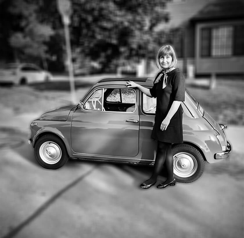 Debora Pearson posing next to a vintage automobile